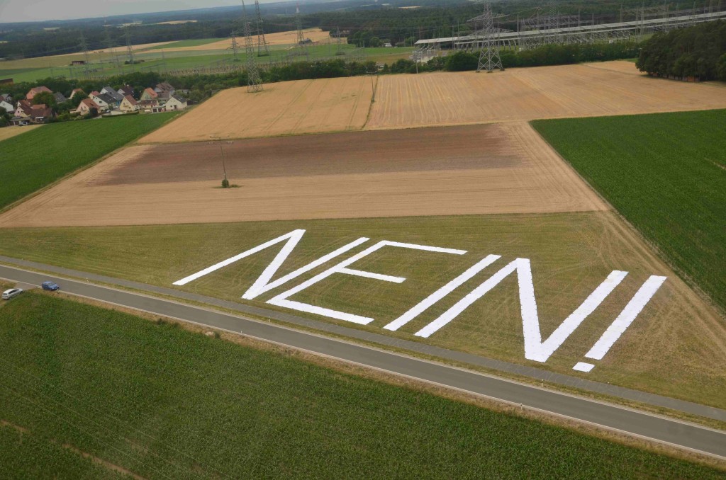 Die von Stromleitungen überspannte Fläche wird hier deutlich. Die Höhe der Buchstaben entspricht der Breite der Mastausleger: 40 Meter. Die Höhe der neuen  Masten: 75 Meter.